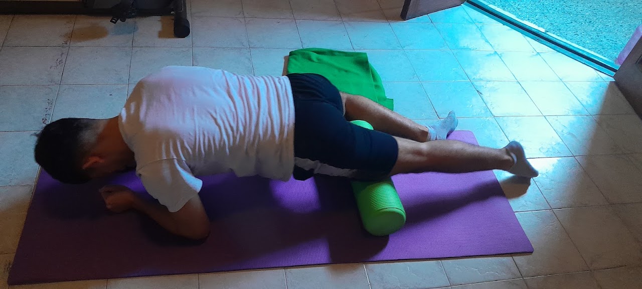 Paciente haciendo un ejercicio de kinesiología con rodillo de espuma en el consultorio de Kinesiologia UBA.