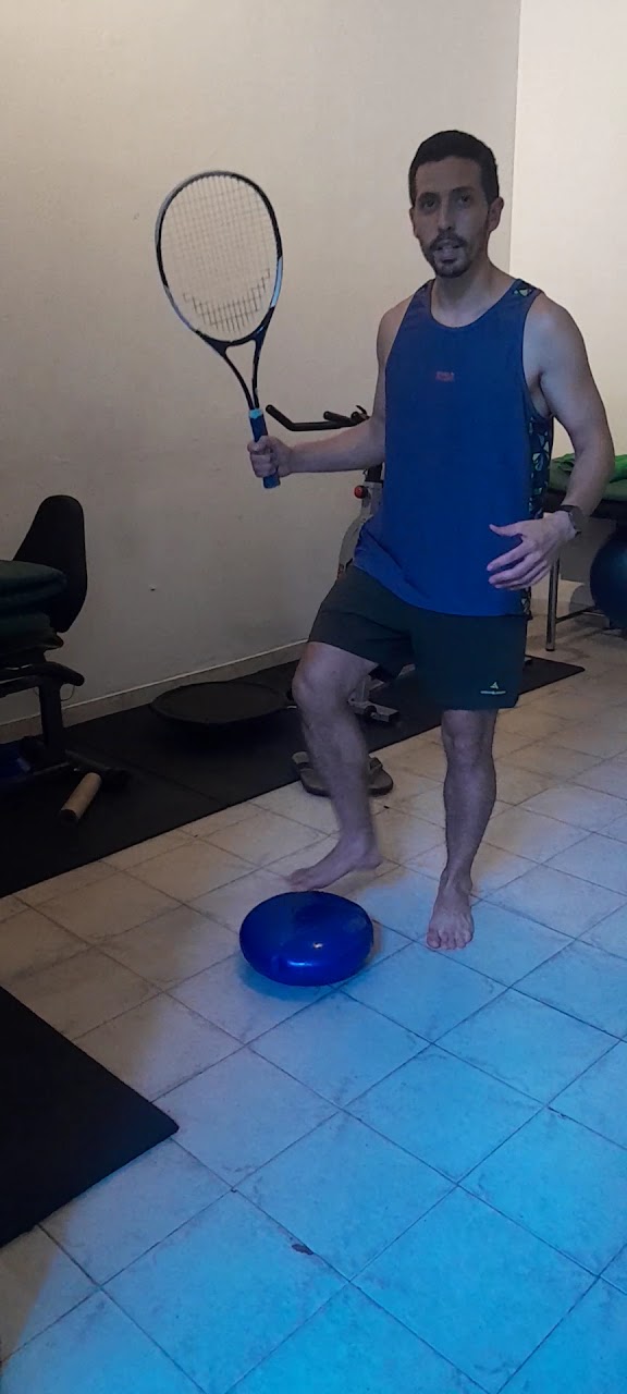 Paciente trabajando estabilidad con raqueta sobre un bosu en el consultorio.